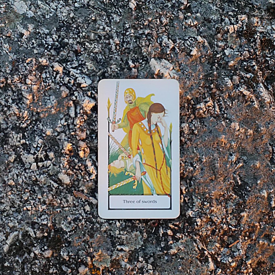 The Three of Swords tarot card photographed outdoors