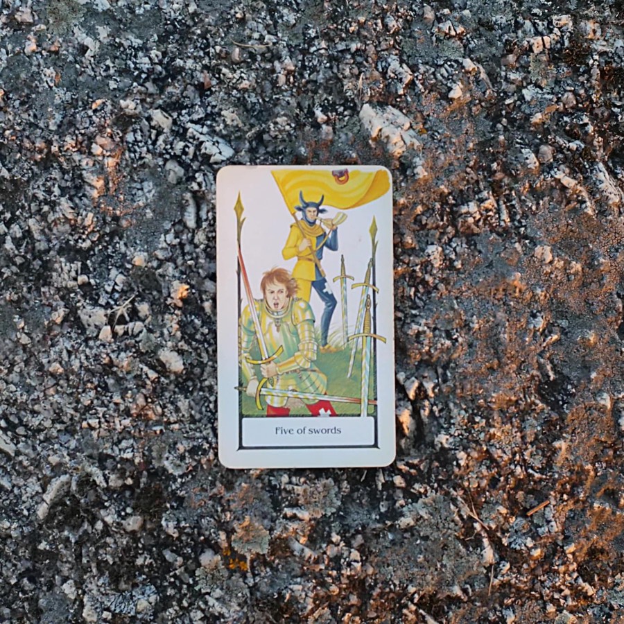 The Five of Swords tarot card photographed outdoors