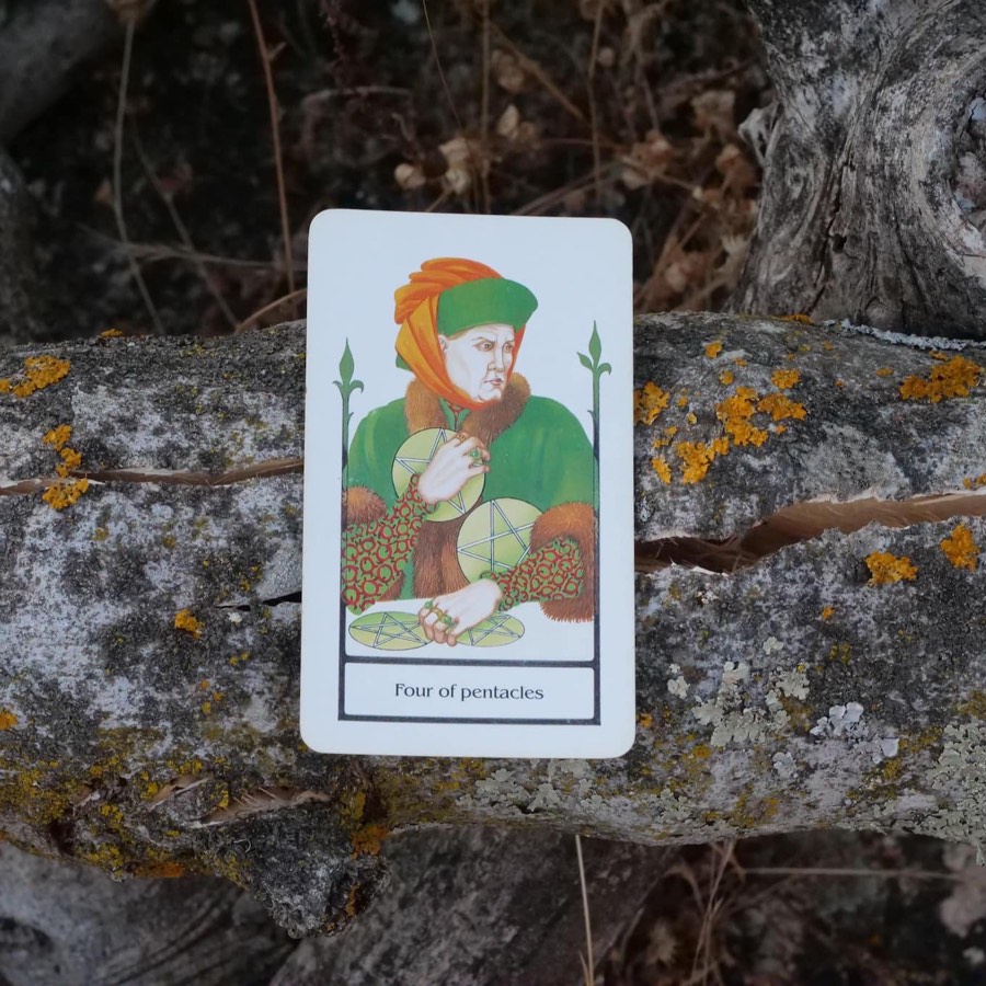 The Four of Pentacles tarot card photographed outdoors