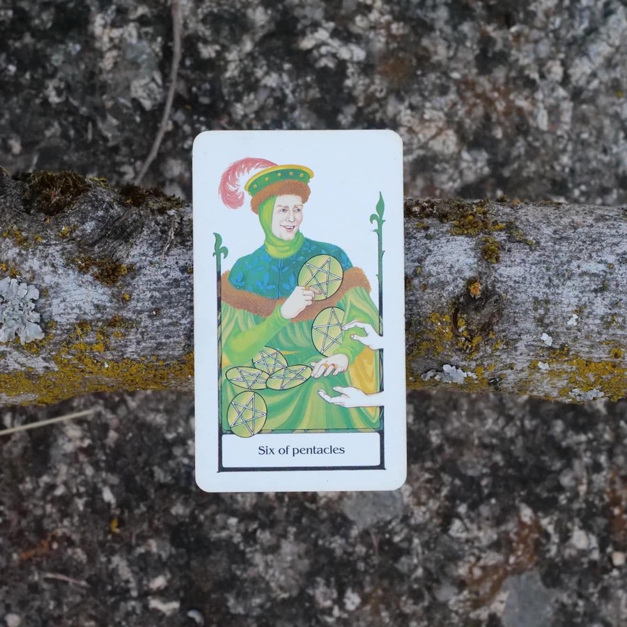 The Six of Pentacles tarot card photographed outdoors