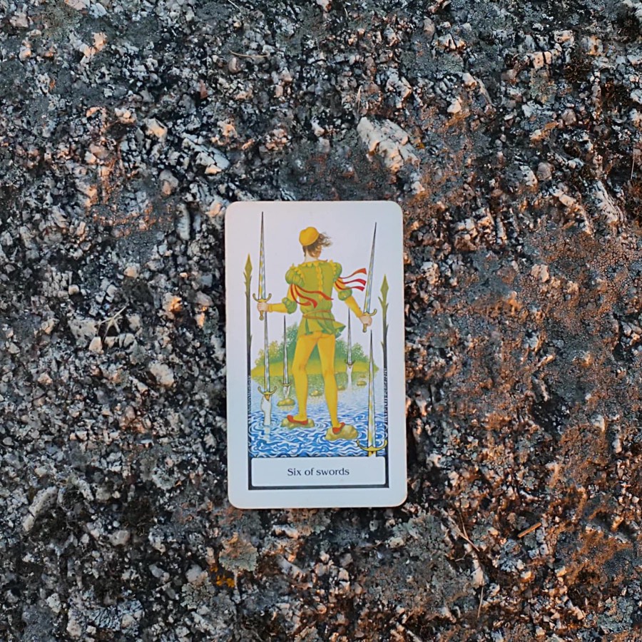 The Six of Swords tarot card photographed outdoors