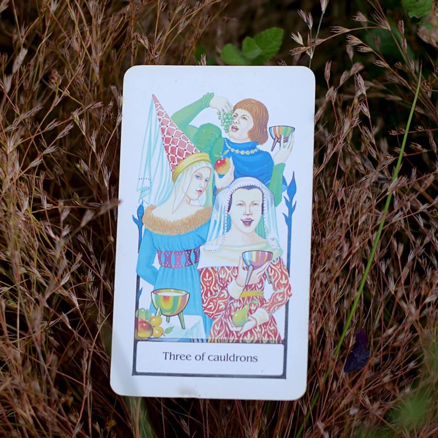 The Three of Cups tarot card photographed outdoors